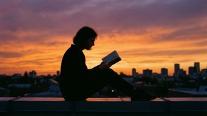 A silhouette reading on a rooftop during a beautiful sunset.